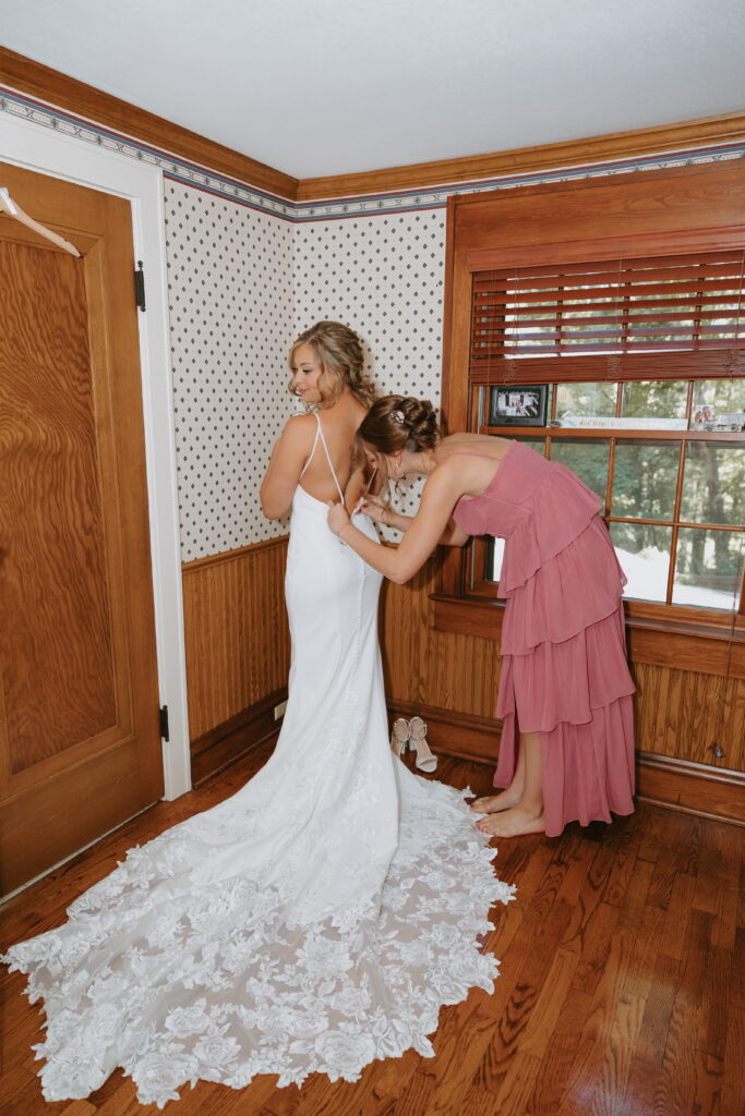 morgan getting her wedding dress on with her bridesmaid helping