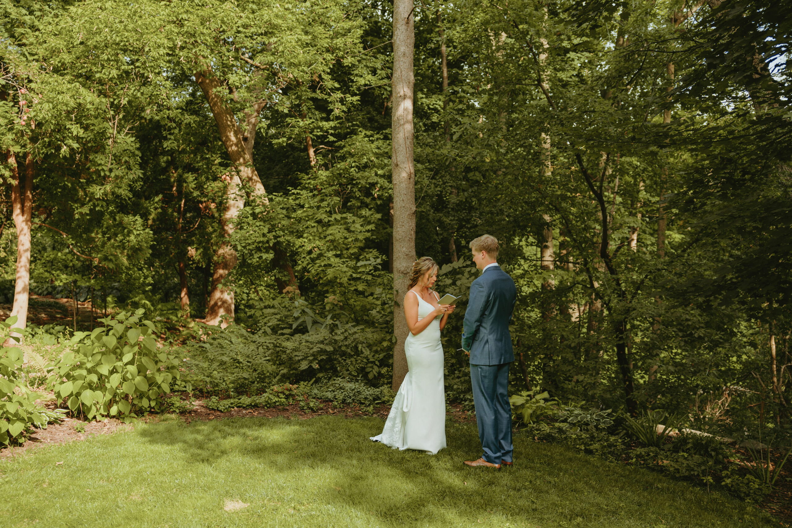 morgan and grant during their first look surrounded by nature in grooms parents backyard reading their vows