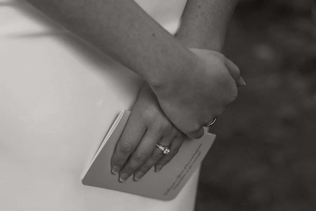 close up black and white of bride holding her vow book closed listening to grooms vows