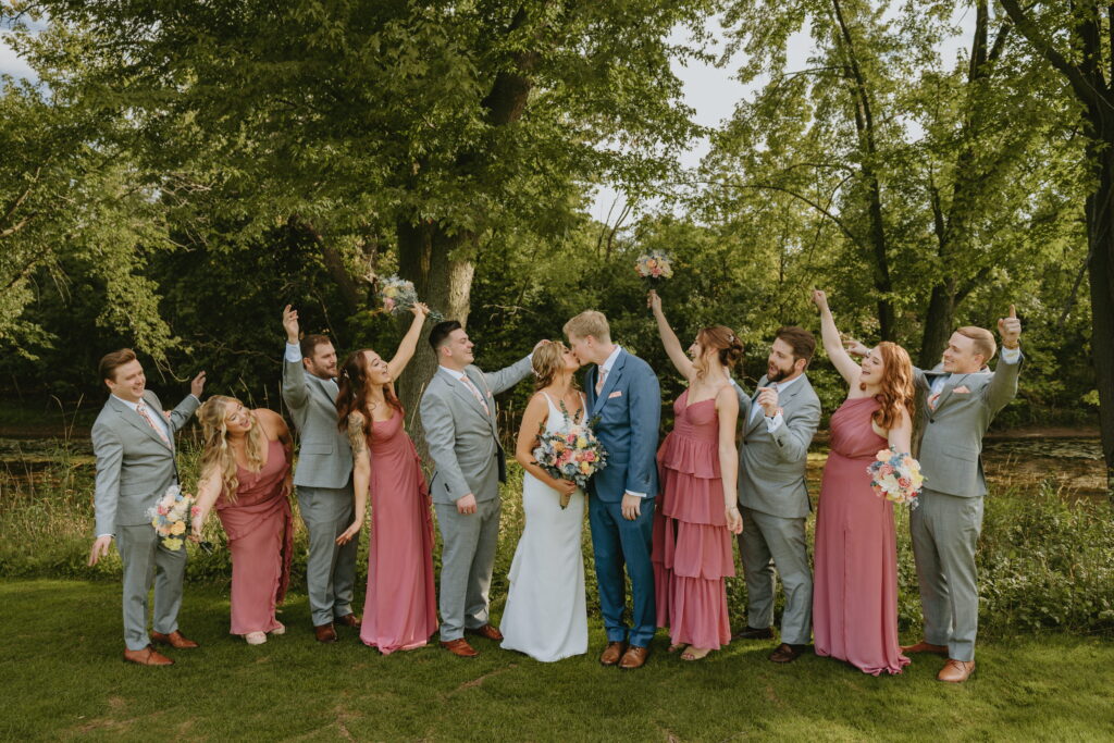 wedding party photo cheering for bride and groom at butte des morts bride and groom are kissing