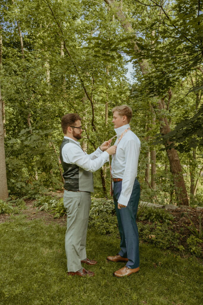 grooms brother tying his tie and helping Grant get ready for his first look