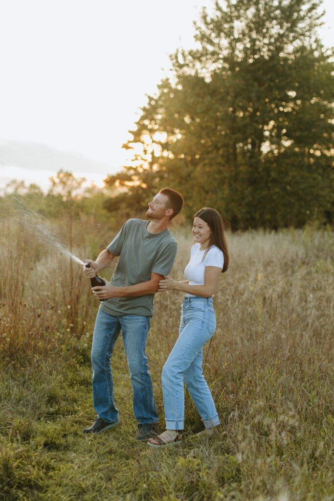 couple popped champagne for their engagement photos in a field in wisconsin