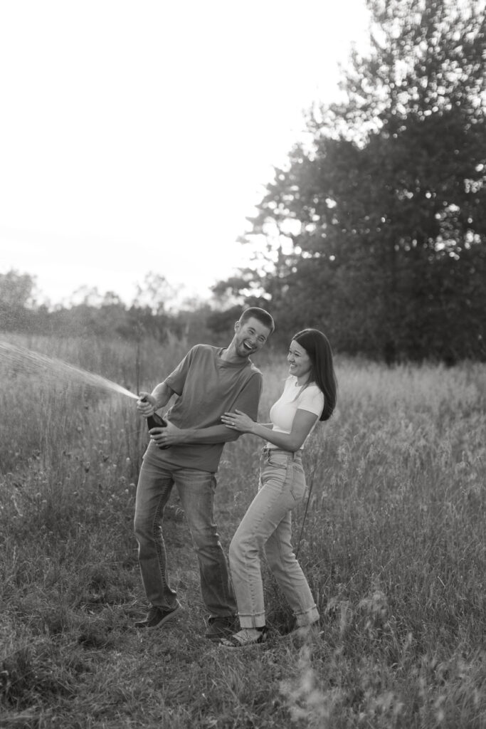 couple popped champagne for their engagement photos in a field in wisconsin