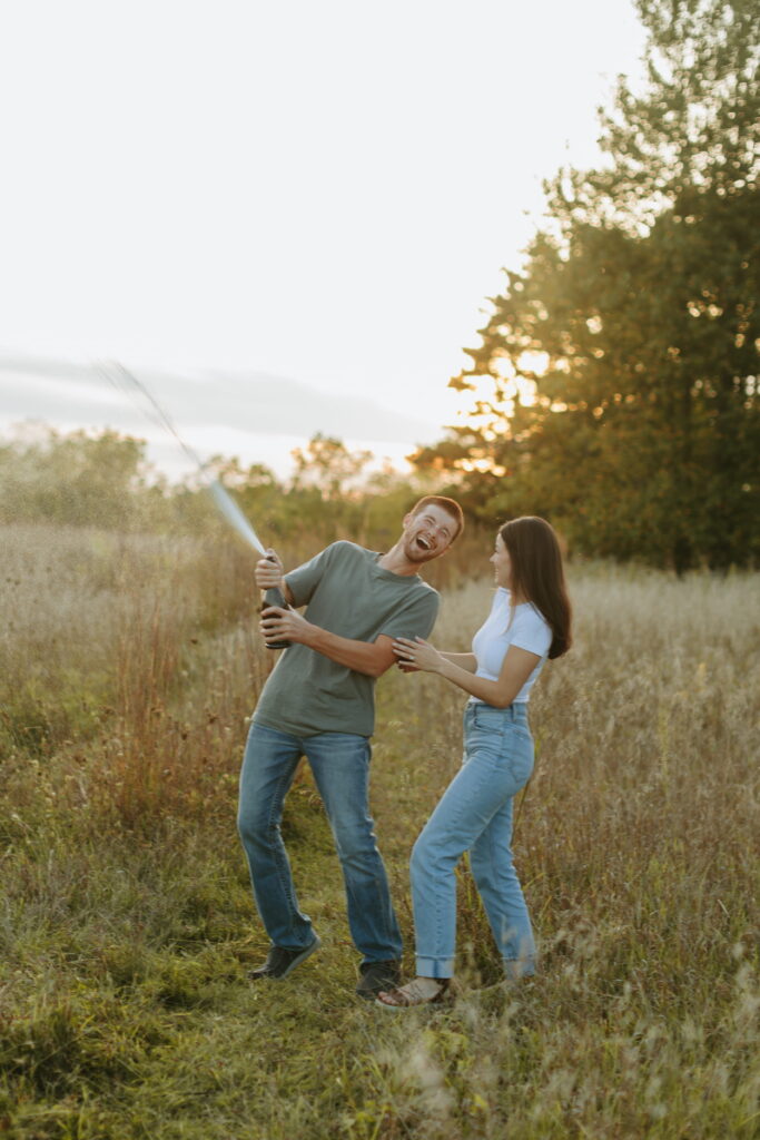 couple popped champagne for their engagement photos in a field in wisconsin