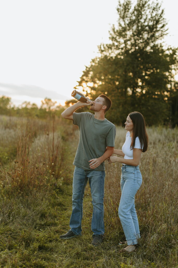 couple popped champagne for their engagement photos in a field in wisconsin