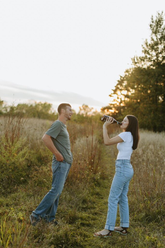 couple popped champagne for their engagement photos in a field in wisconsin