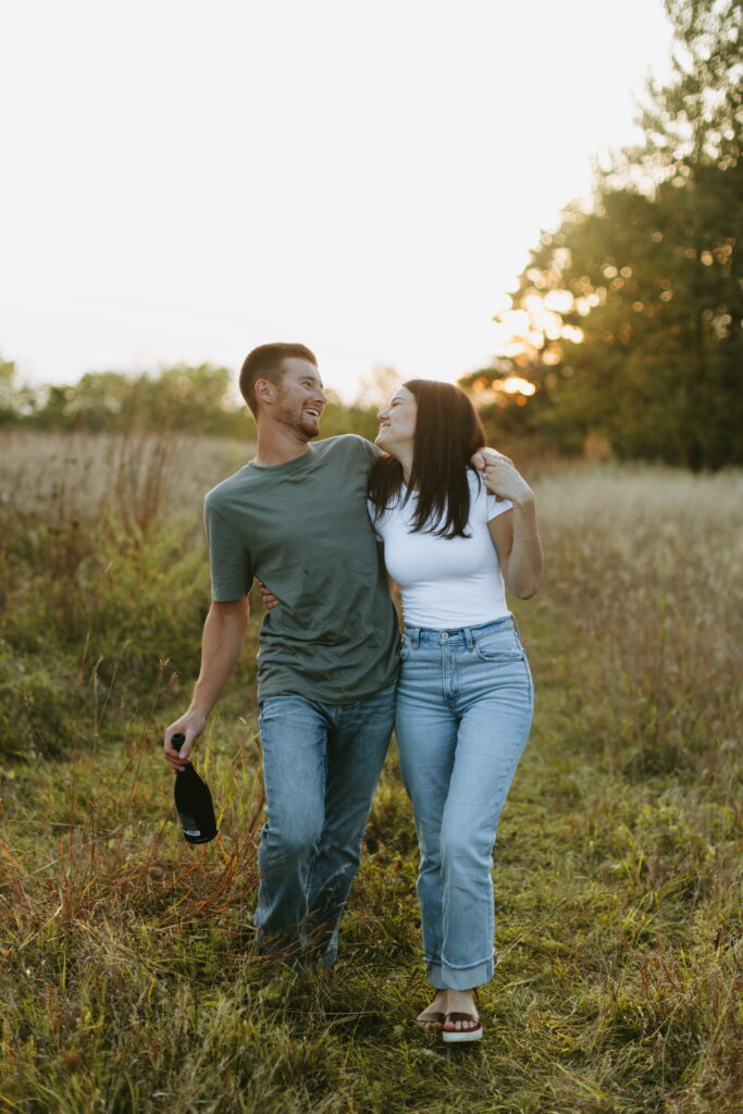 couple popped champagne for their engagement photos in a field in wisconsin
