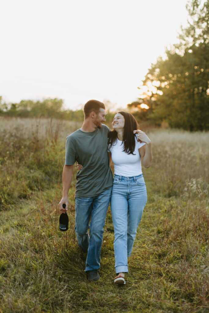 couple popped champagne for their engagement photos in a field in wisconsin