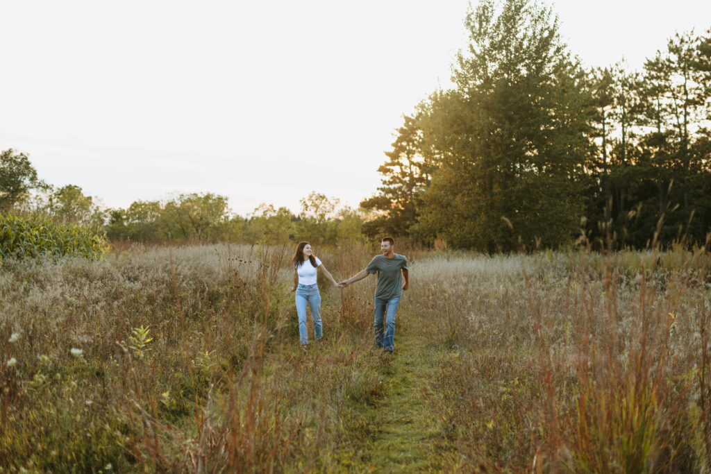 couple running towards camera at sunset to finish off engagement photos in a wisconsin field