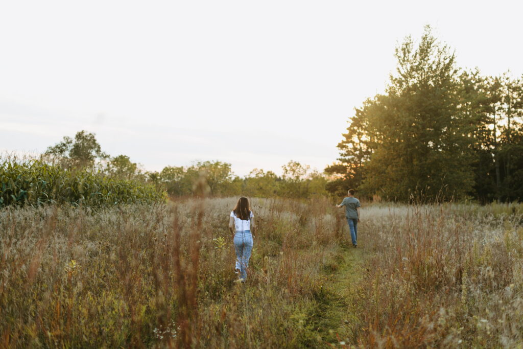 couple running at sunset to finish off engagement photos in a wisconsin field