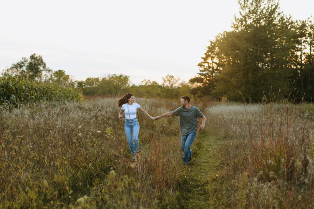 couple running at sunset to finish off engagement photos in a wisconsin field