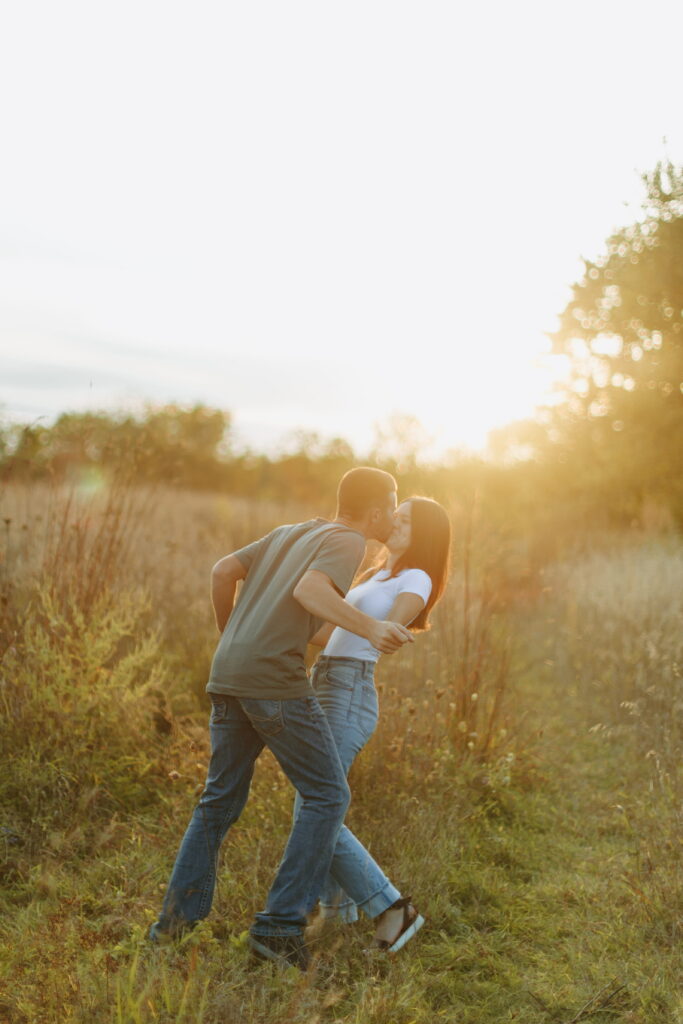 couple posing candids in field for engagement photos in wisconsin