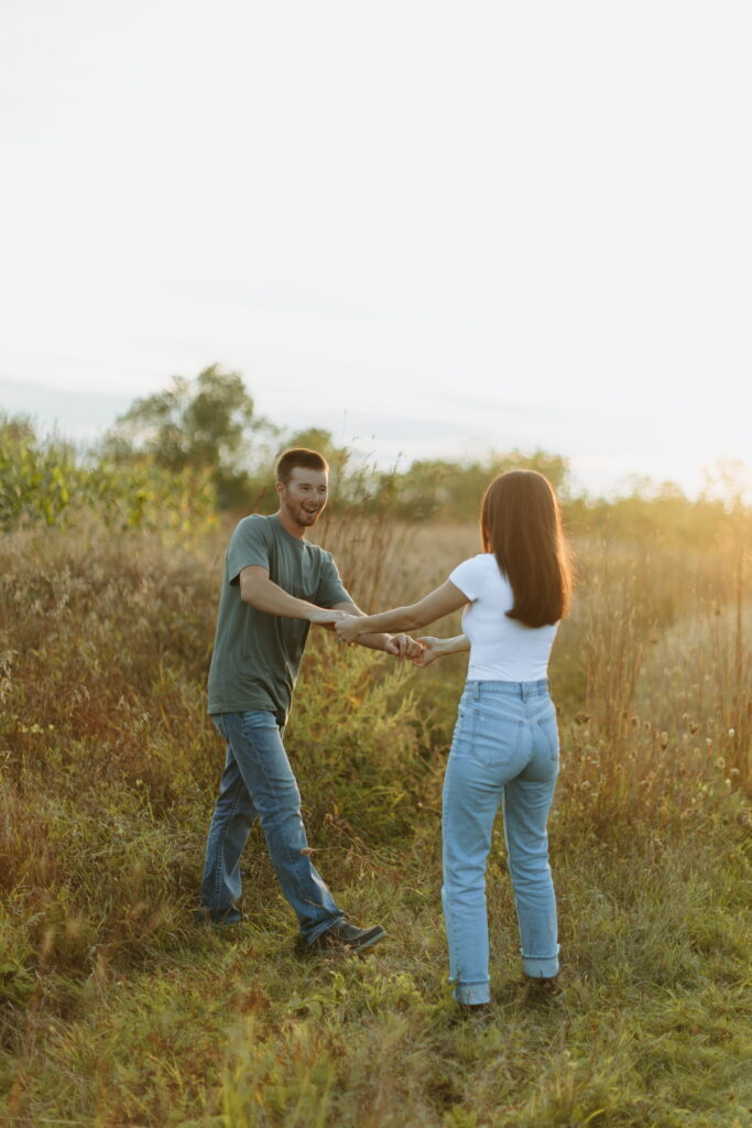 couple posing candids in field for engagement photos in wisconsin