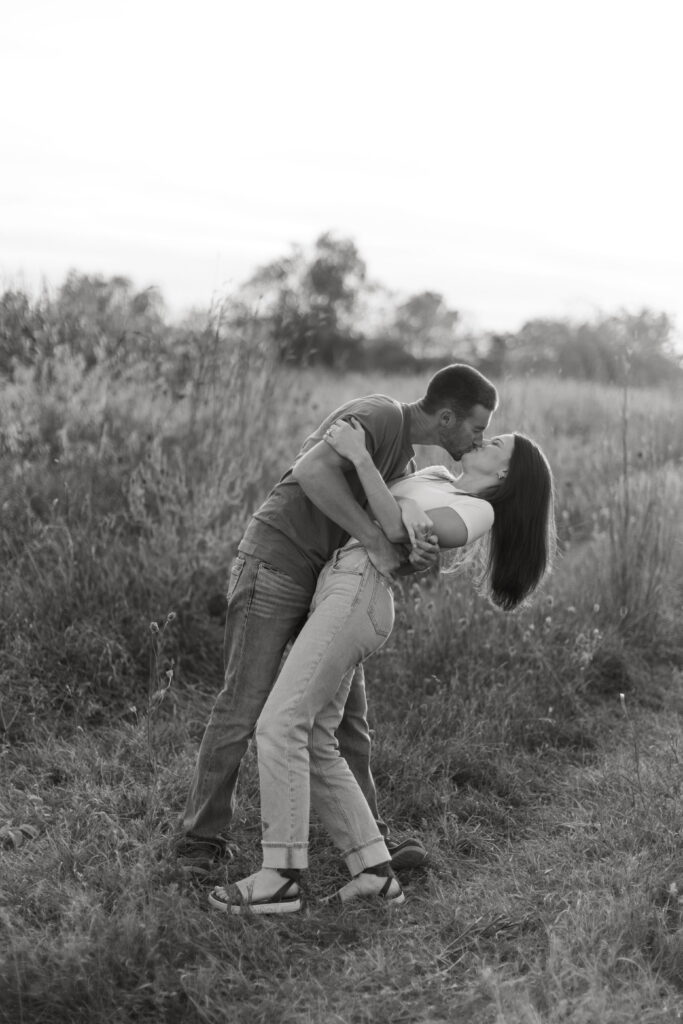 couple posing candids in field for engagement photos in wisconsin