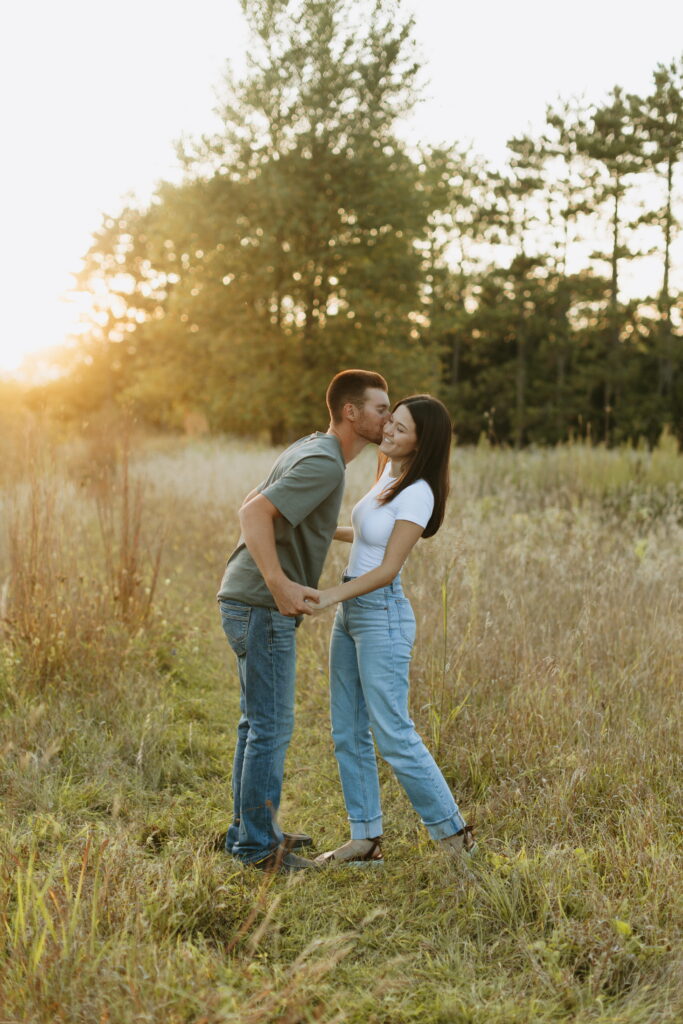 couple posing candids in field for engagement photos in wisconsin