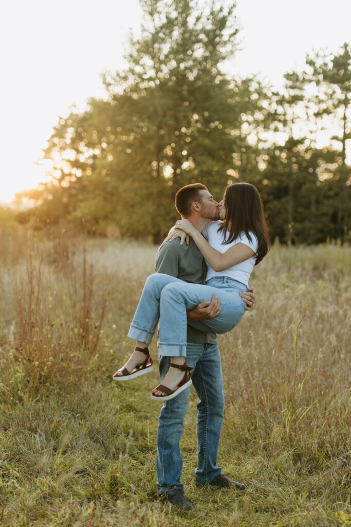 couple posing candids in field for engagement photos in wisconsin