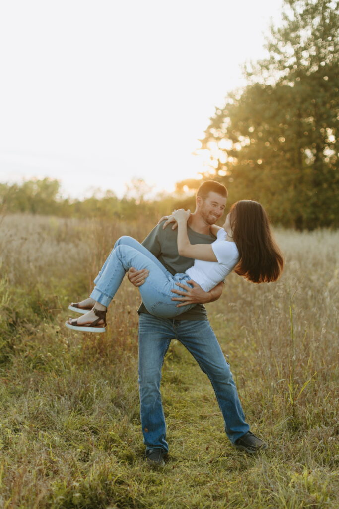 couple posing candids in field for engagement photos in wisconsin