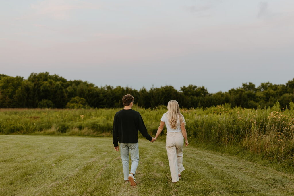couple walking away from camera in field at blue hour