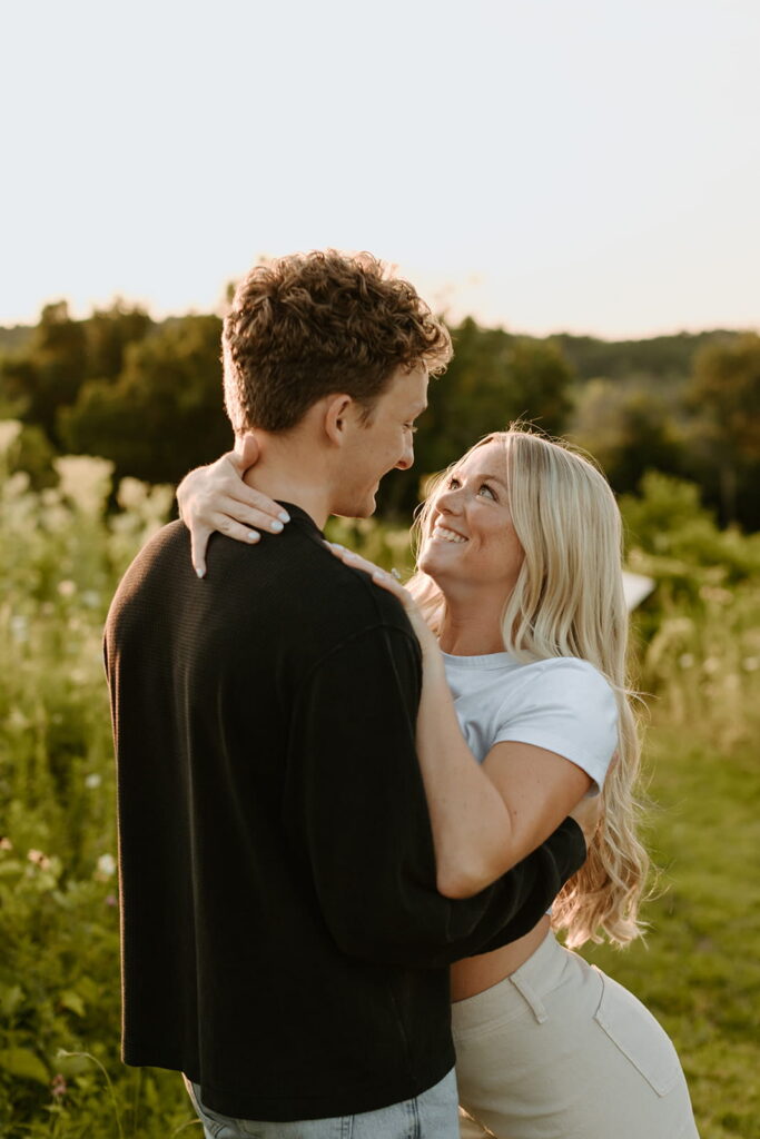 couple smiling into eachothers eyes with field